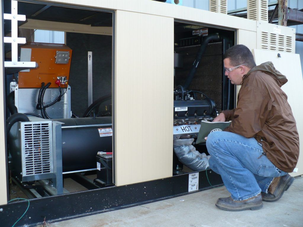 A man in a brown jacket is working on a generator