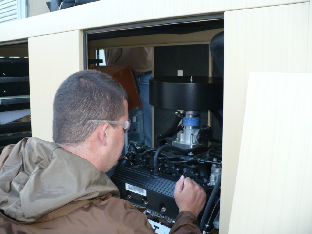 A man in a brown jacket is working on a machine