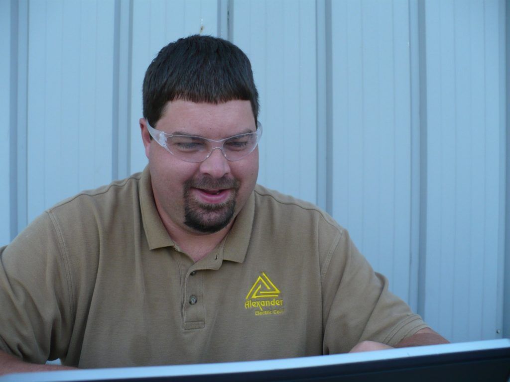 A man wearing safety goggles is looking at a computer screen.