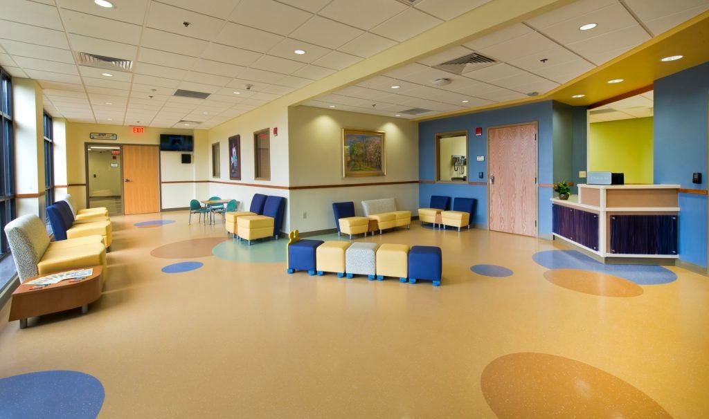 A hospital waiting room with colorful chairs and ottomans