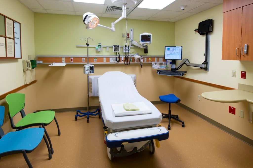 An empty hospital room with a bed and chairs