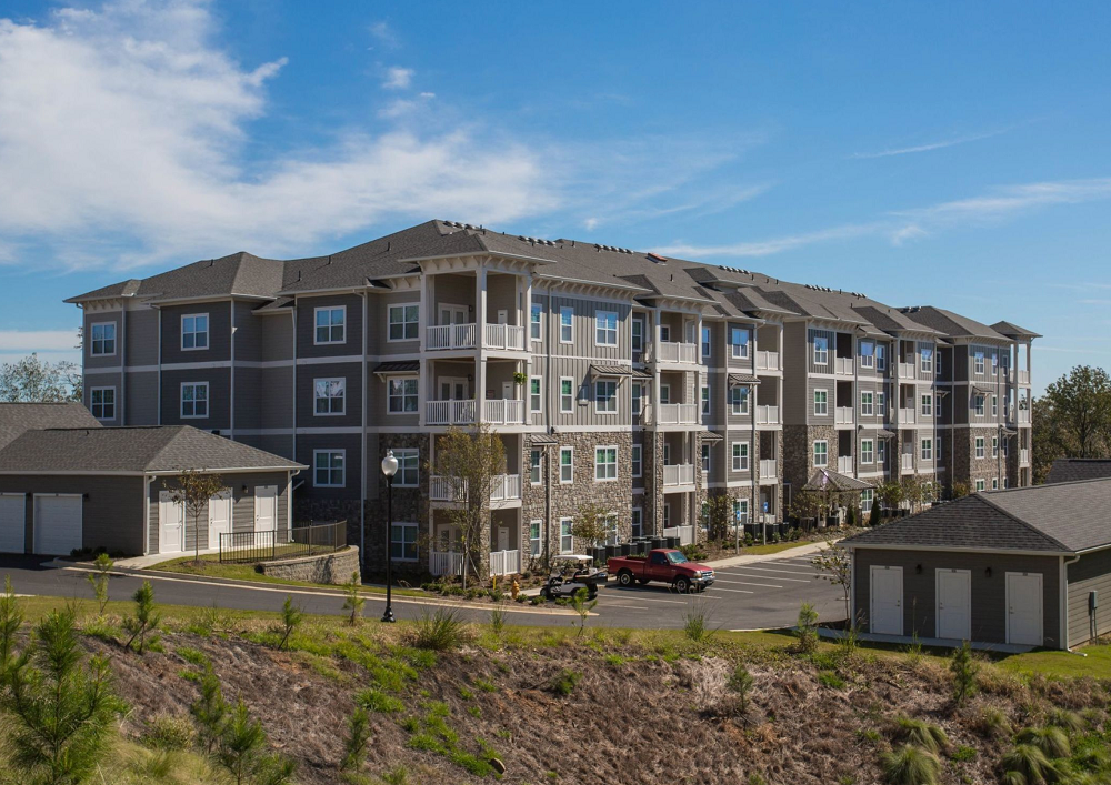 A large apartment building with a red car parked in front of it.