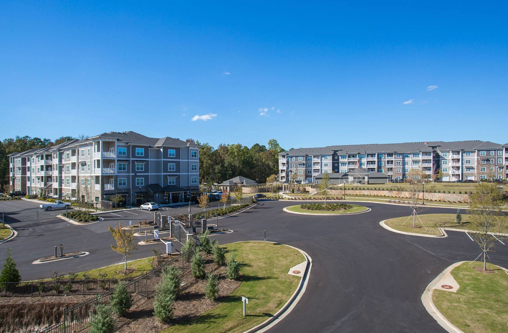 An aerial view of a large apartment building with a parking lot in front of it.