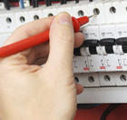 A person is using a multimeter to test a circuit breaker