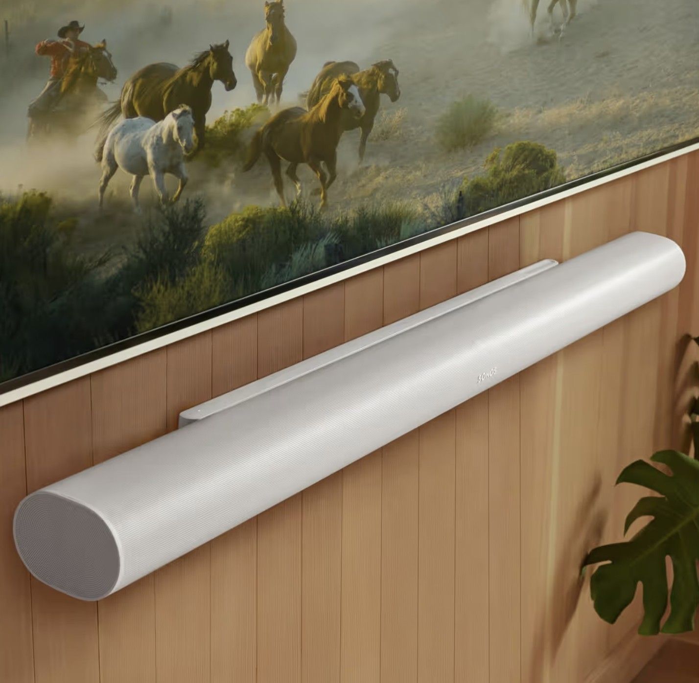 A painting of horses is hanging on a wooden wall, with a Sonos Ultra light bar mounted below