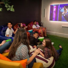 A group of people are sitting on bean bag chairs in front of a projector screen.
