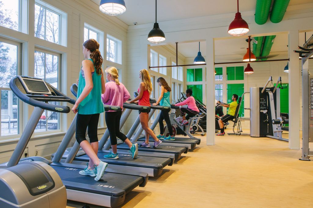A group of young girls are running on treadmills in a gym.
