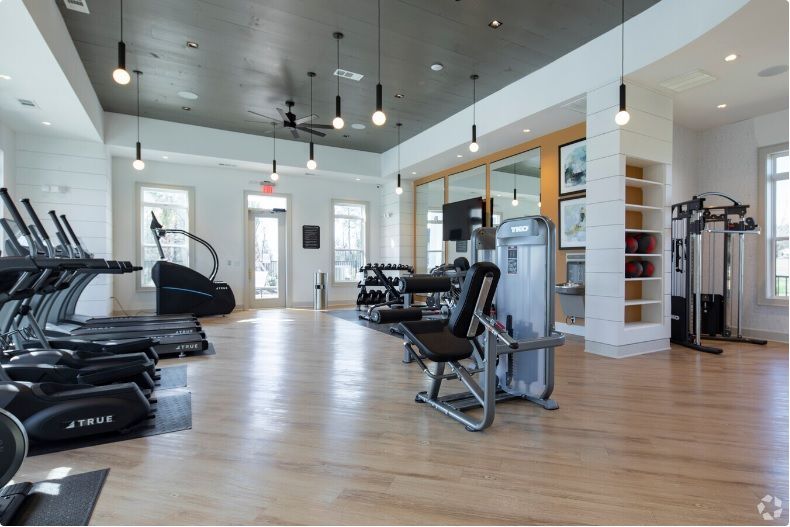 A large gym with a lot of equipment and a wooden floor.