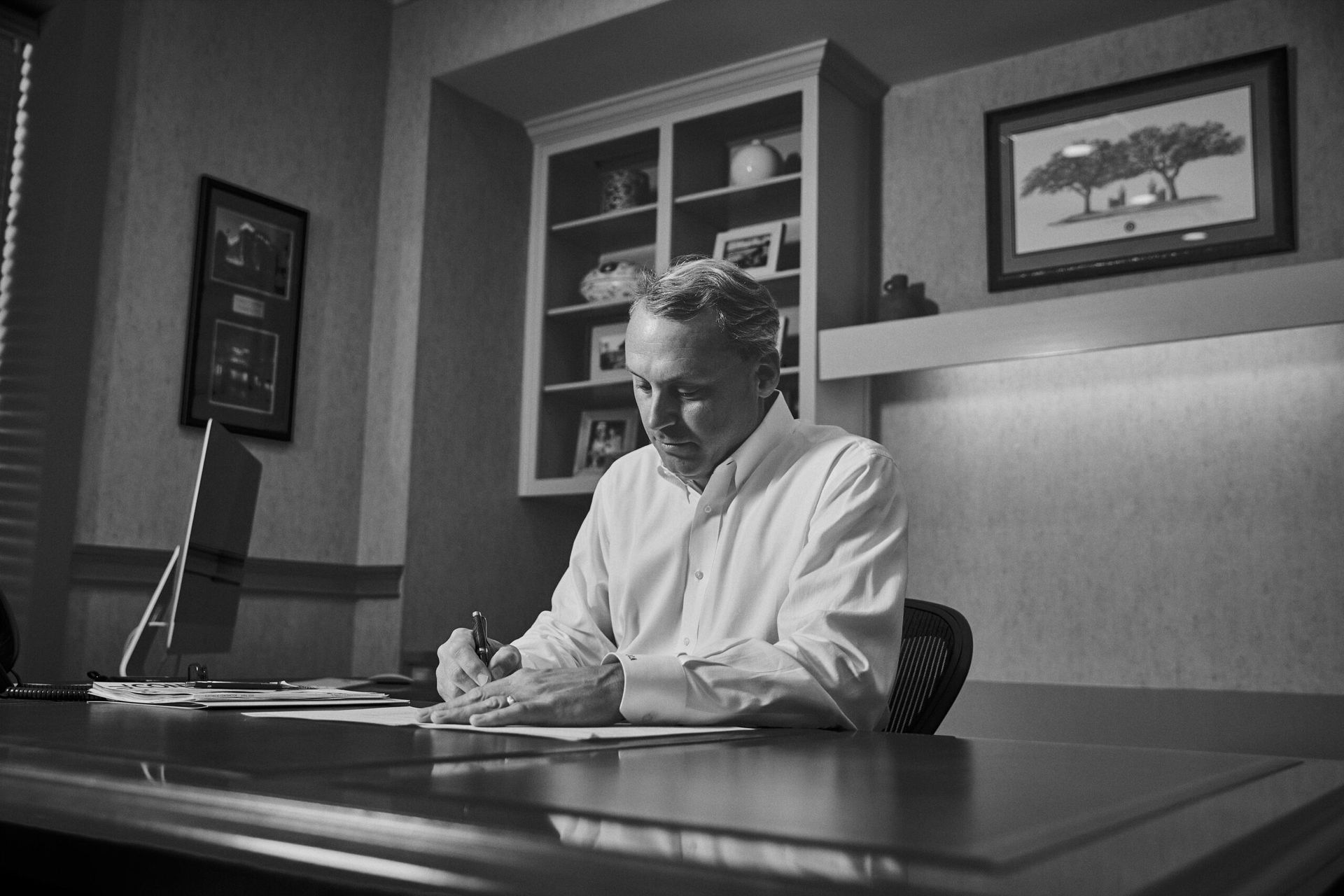 A man is sitting at a desk writing on a piece of paper.