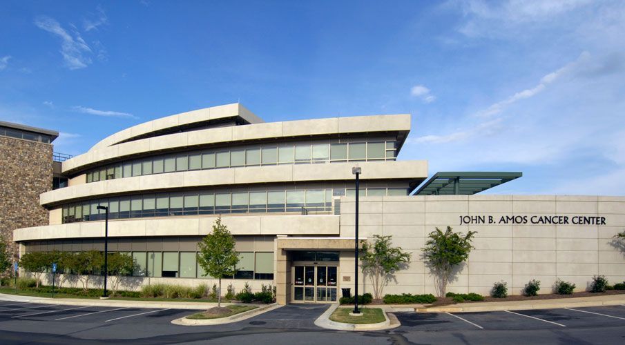 A large building with a lot of windows and a parking lot in front of it.