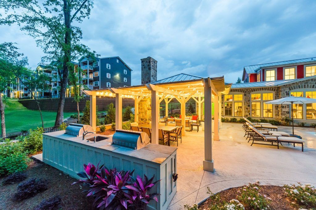 A large patio area with a grill and umbrellas in front of a building.