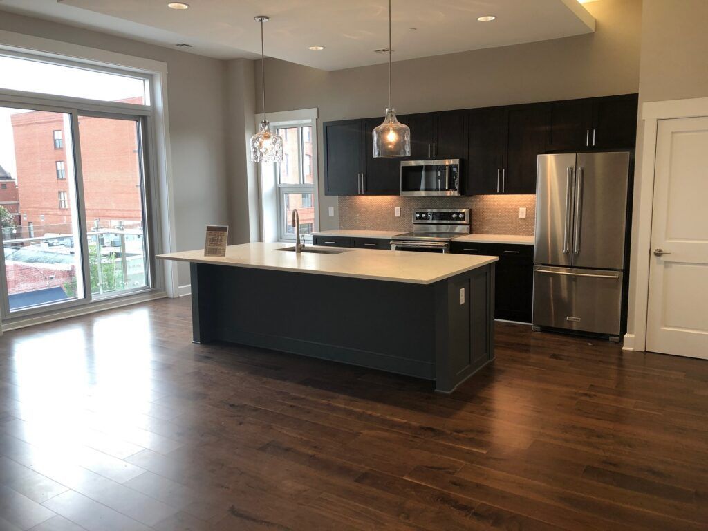 An empty kitchen with a large island and stainless steel appliances