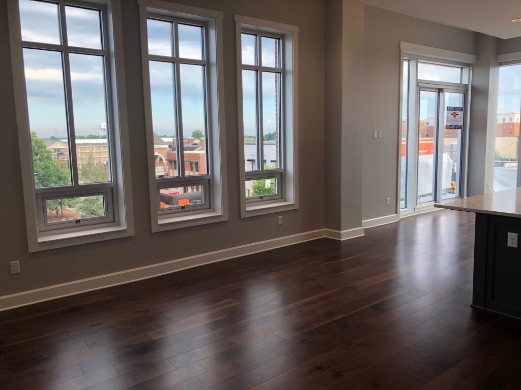 An empty room with hardwood floors and lots of windows