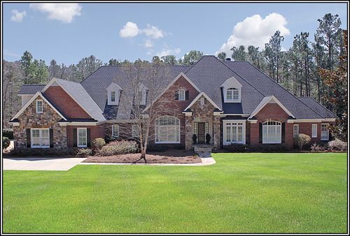 A large brick and stone house with a lush green lawn in front of it