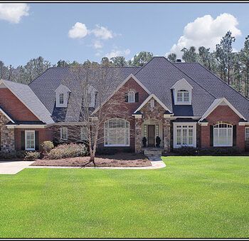 A large brick house with a lush green lawn in front of it