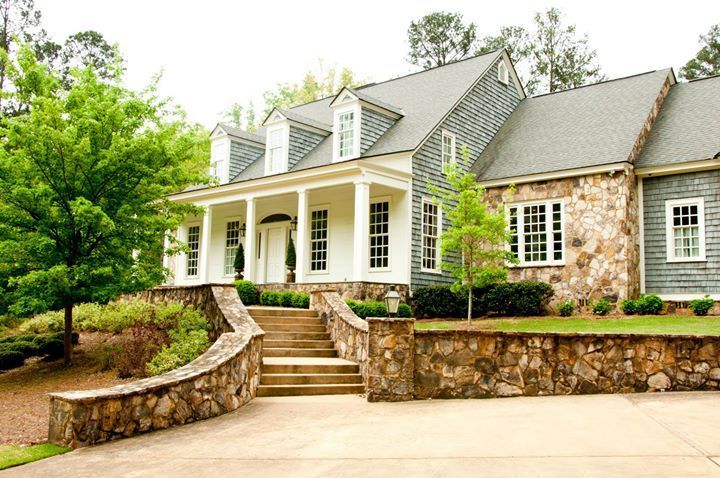 A large house with a stone wall and stairs leading up to it.