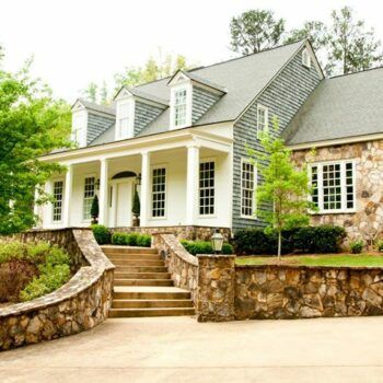 A large house with a stone wall and stairs leading up to it