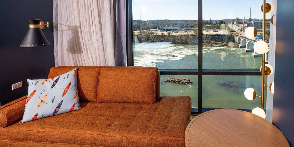 A living room with a couch and a large window overlooking a river.