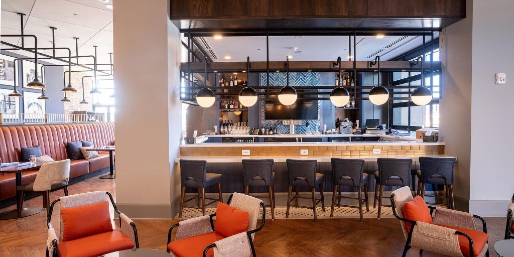 A restaurant with a bar , chairs , tables and a couch.