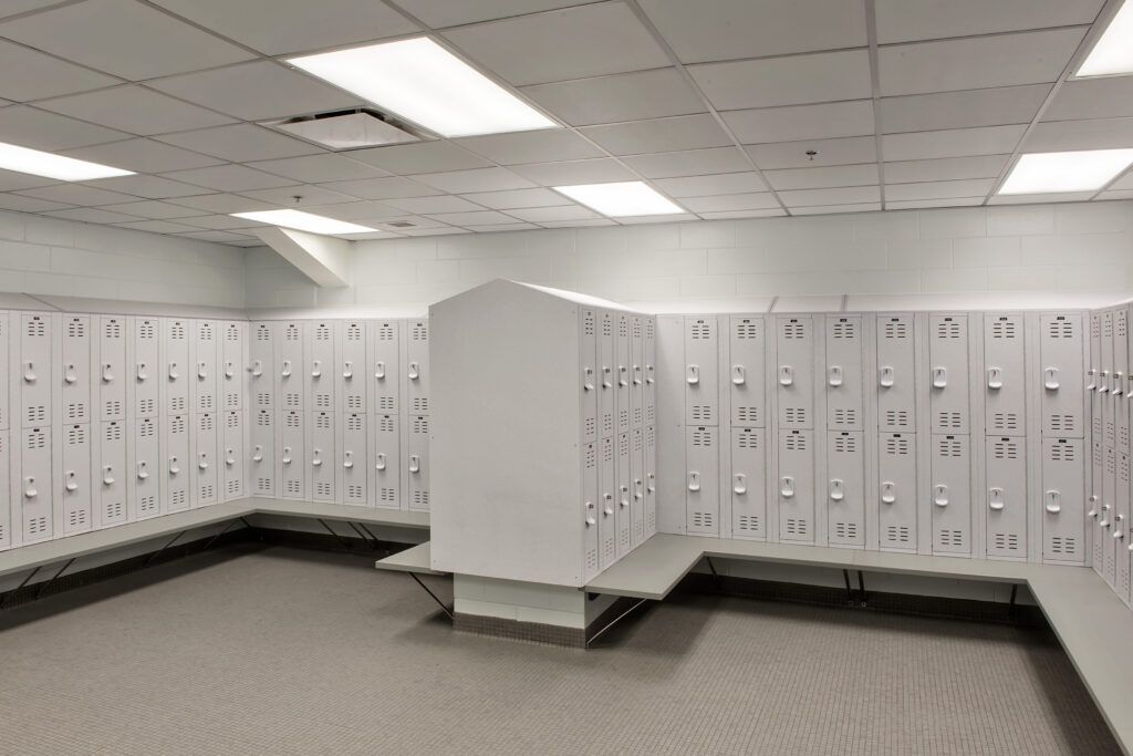 A large locker room filled with lots of white lockers.