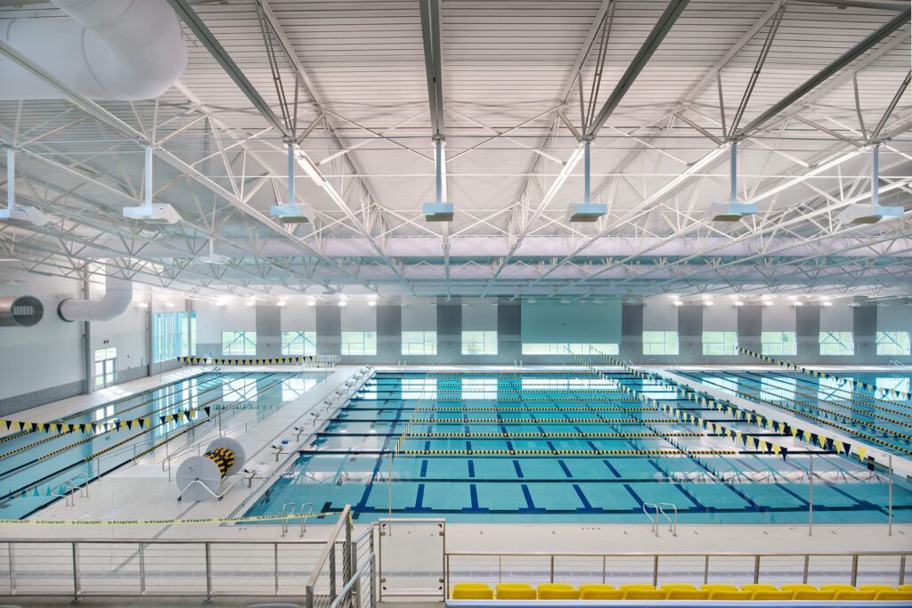 A large indoor swimming pool with a lot of windows and a ceiling.