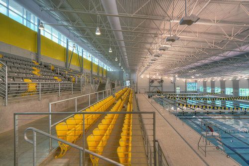 A large indoor swimming pool with yellow seats and stairs leading to it.
