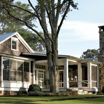 A house with a screened in porch and a stone chimney