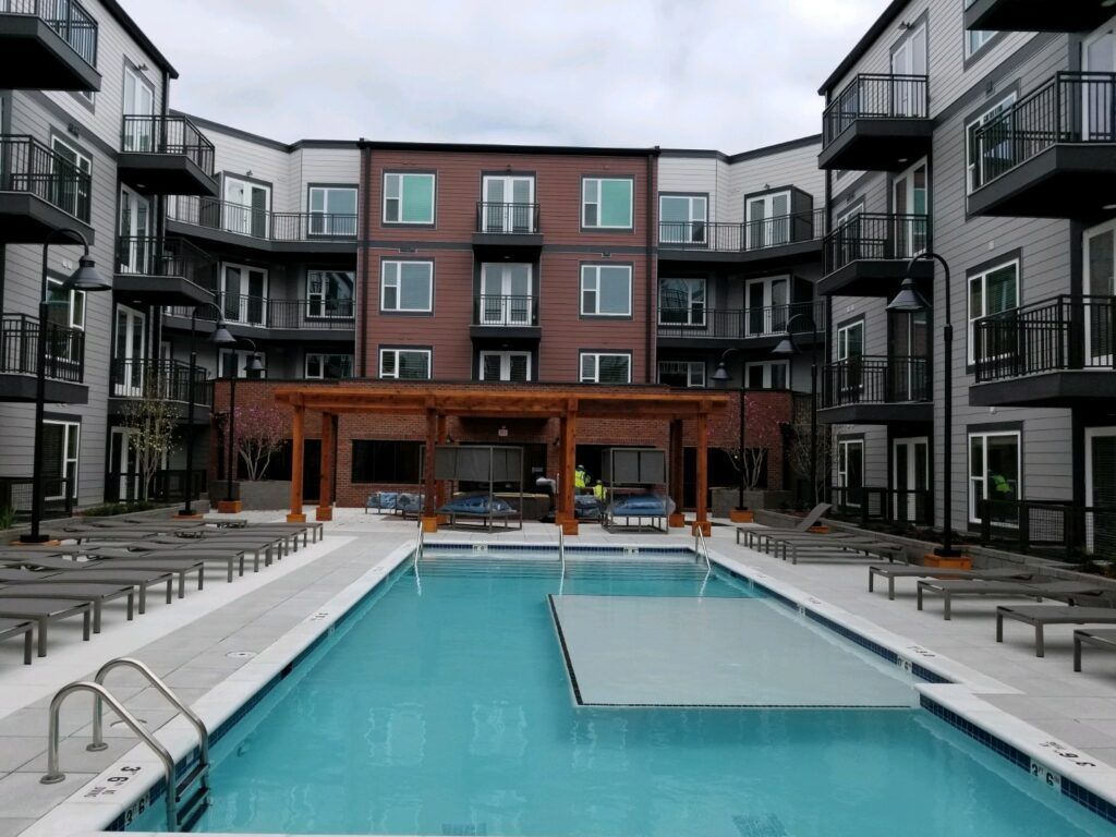 A large swimming pool in front of a large apartment building.