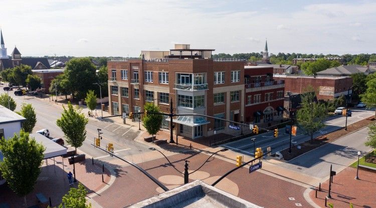 An aerial view of a city intersection with a large building in the background.