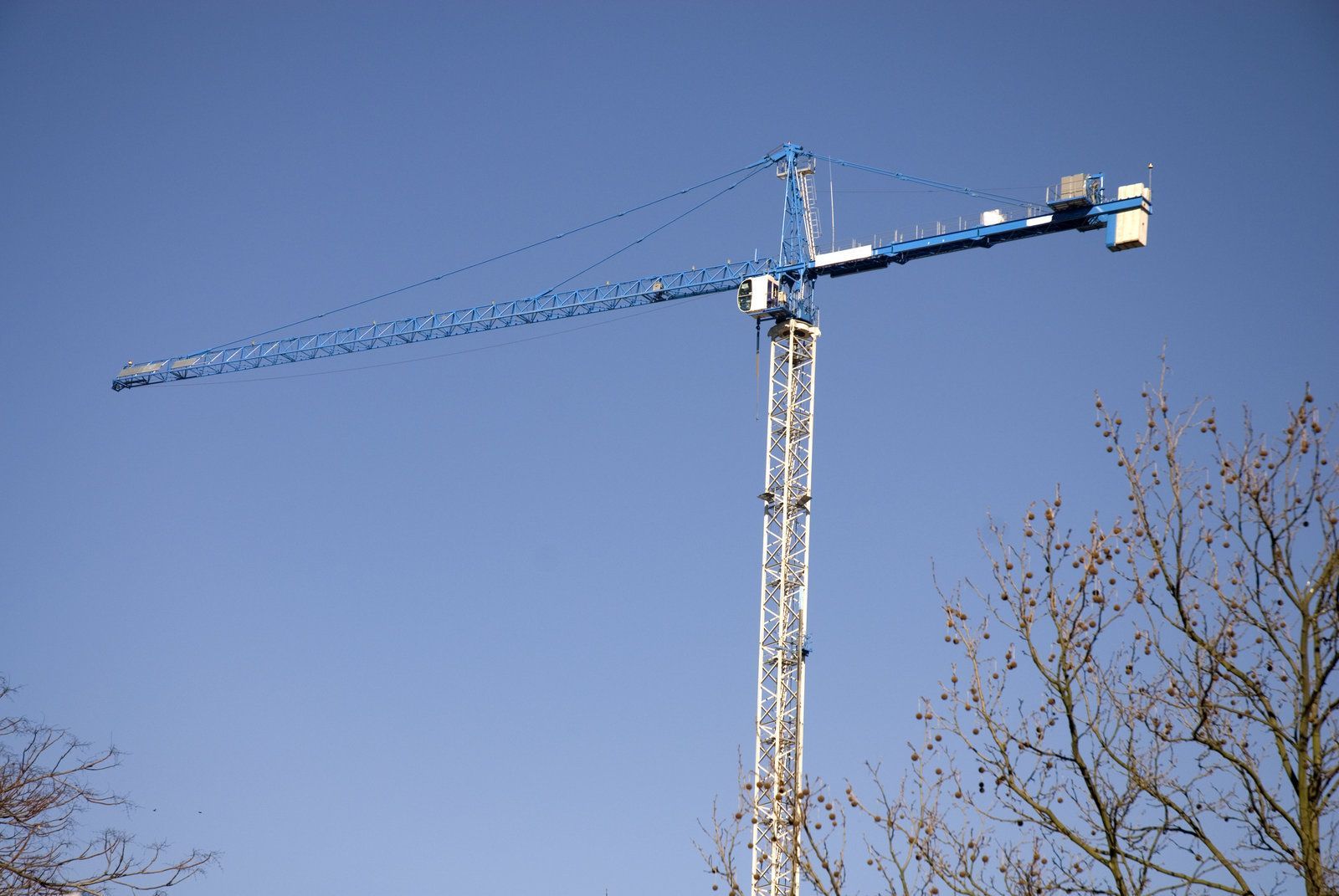 a blue crane is on top of a tall tower