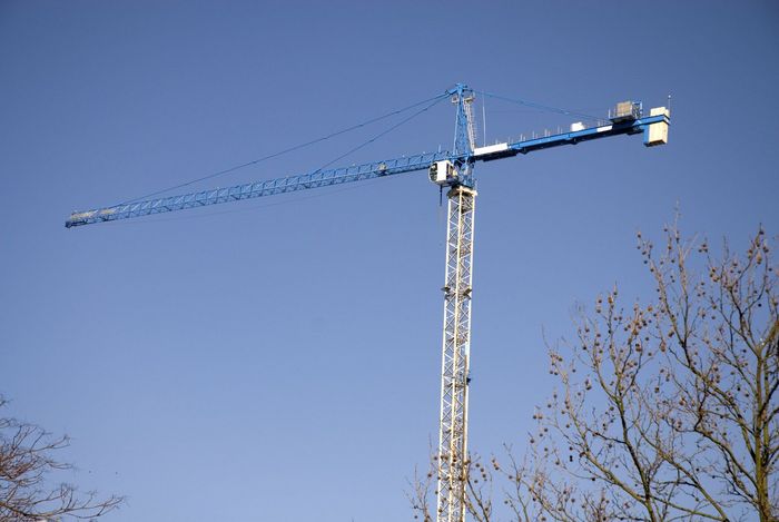 a blue crane is on top of a tall tower