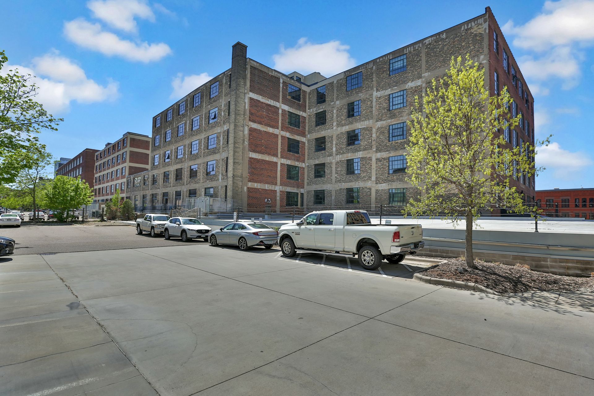 A row of cars are parked in front of a large building.