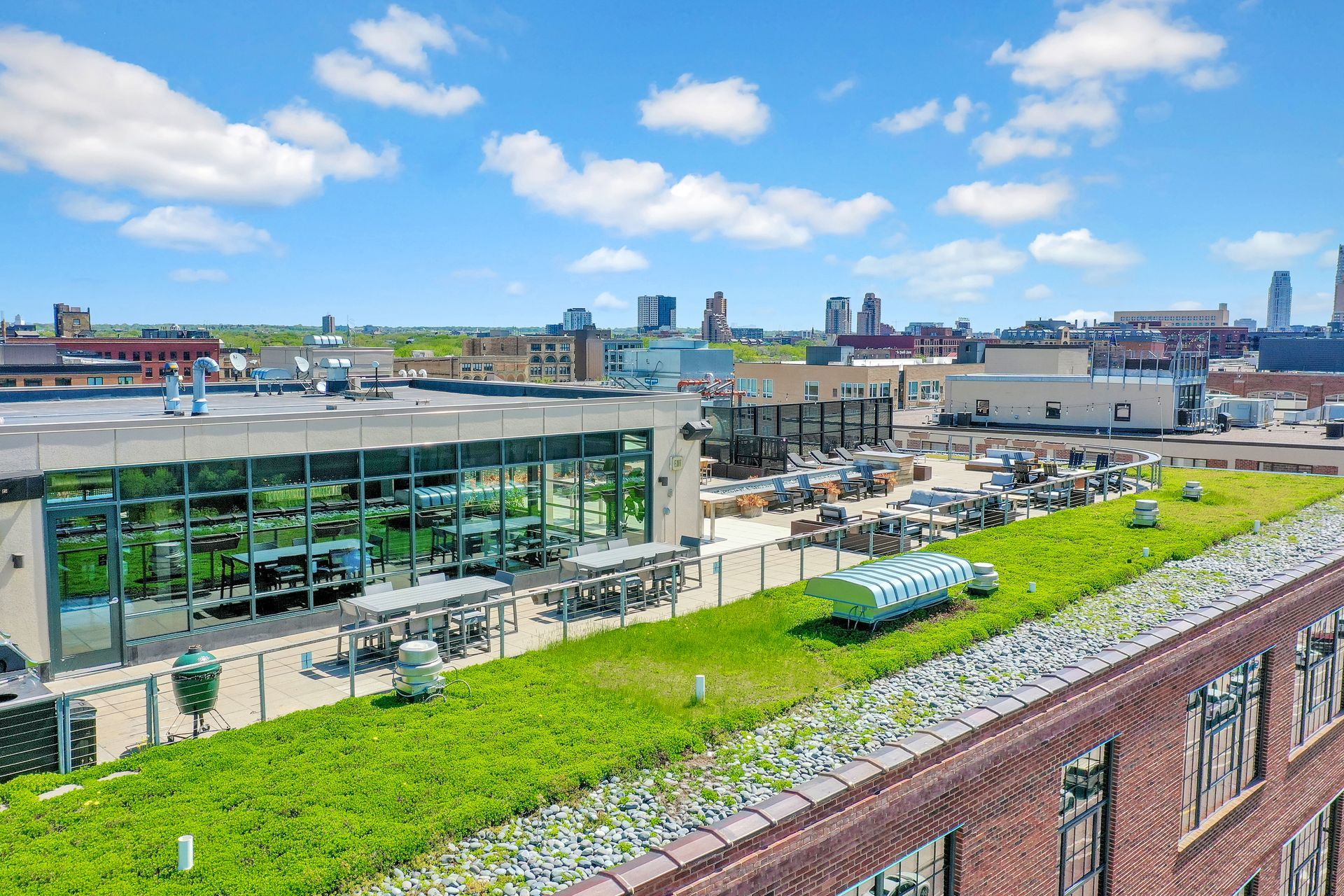 An aerial view of a building with a green roof and a city in the background.