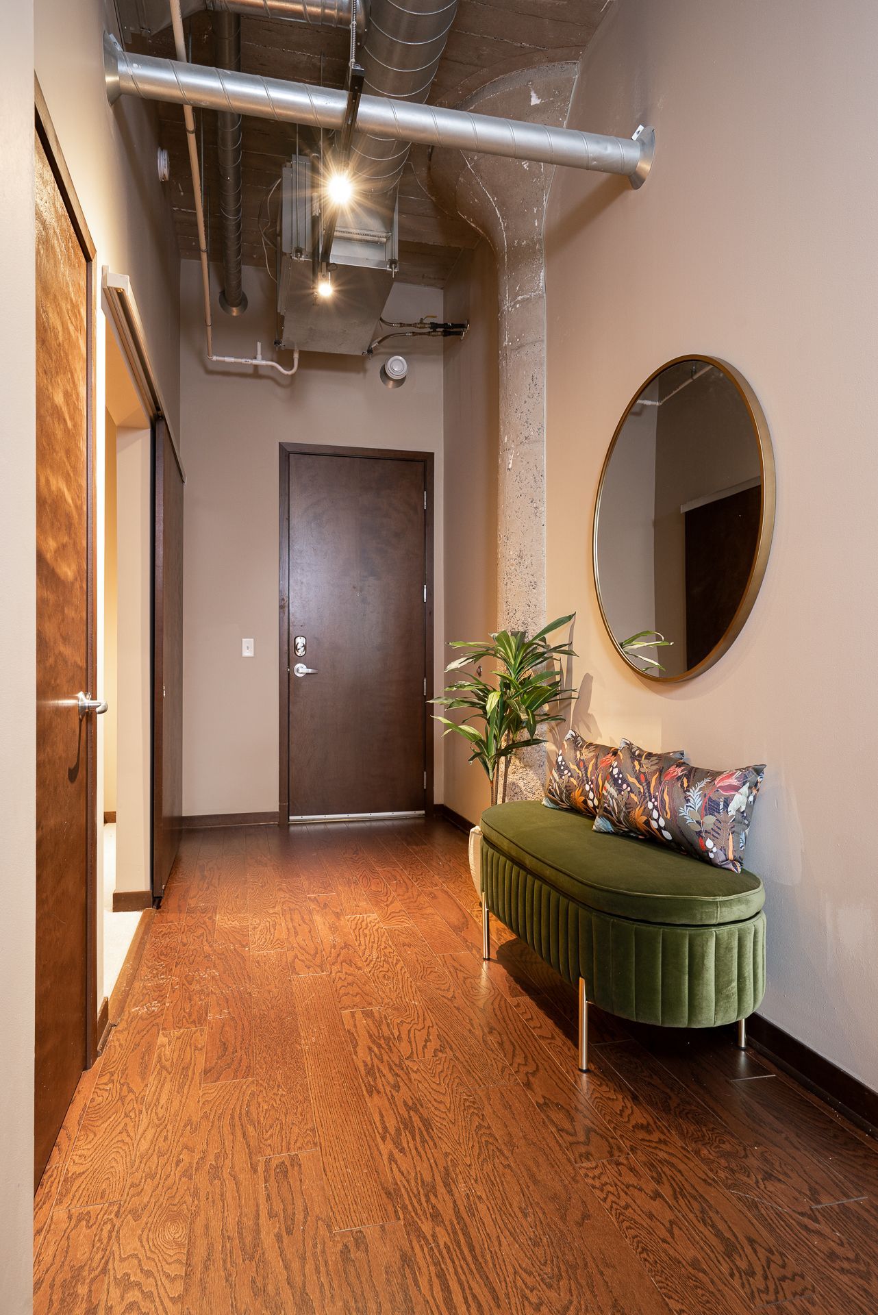 A hallway with a green bench and a mirror on the wall.