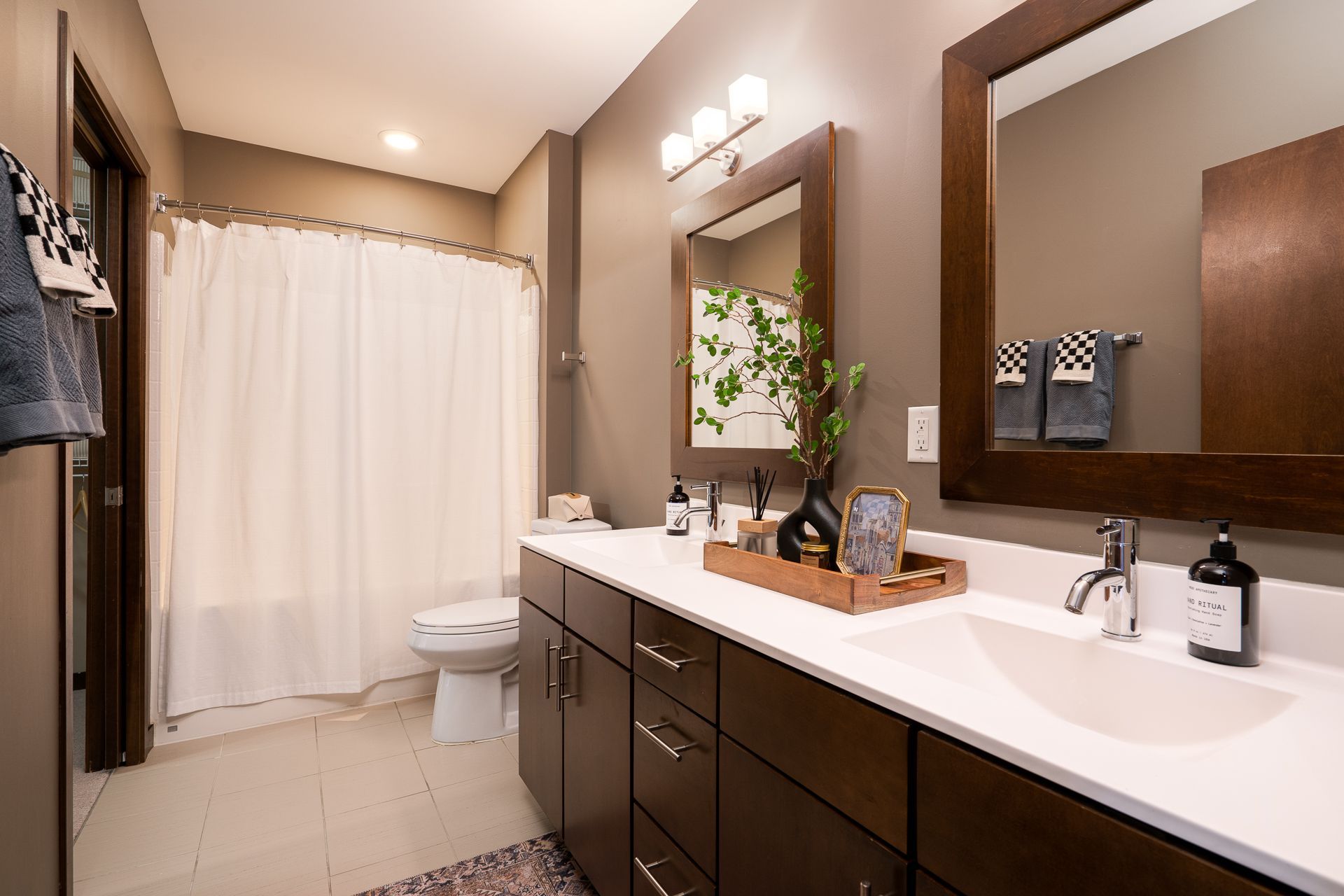 A bathroom with two sinks , a toilet , and a mirror.