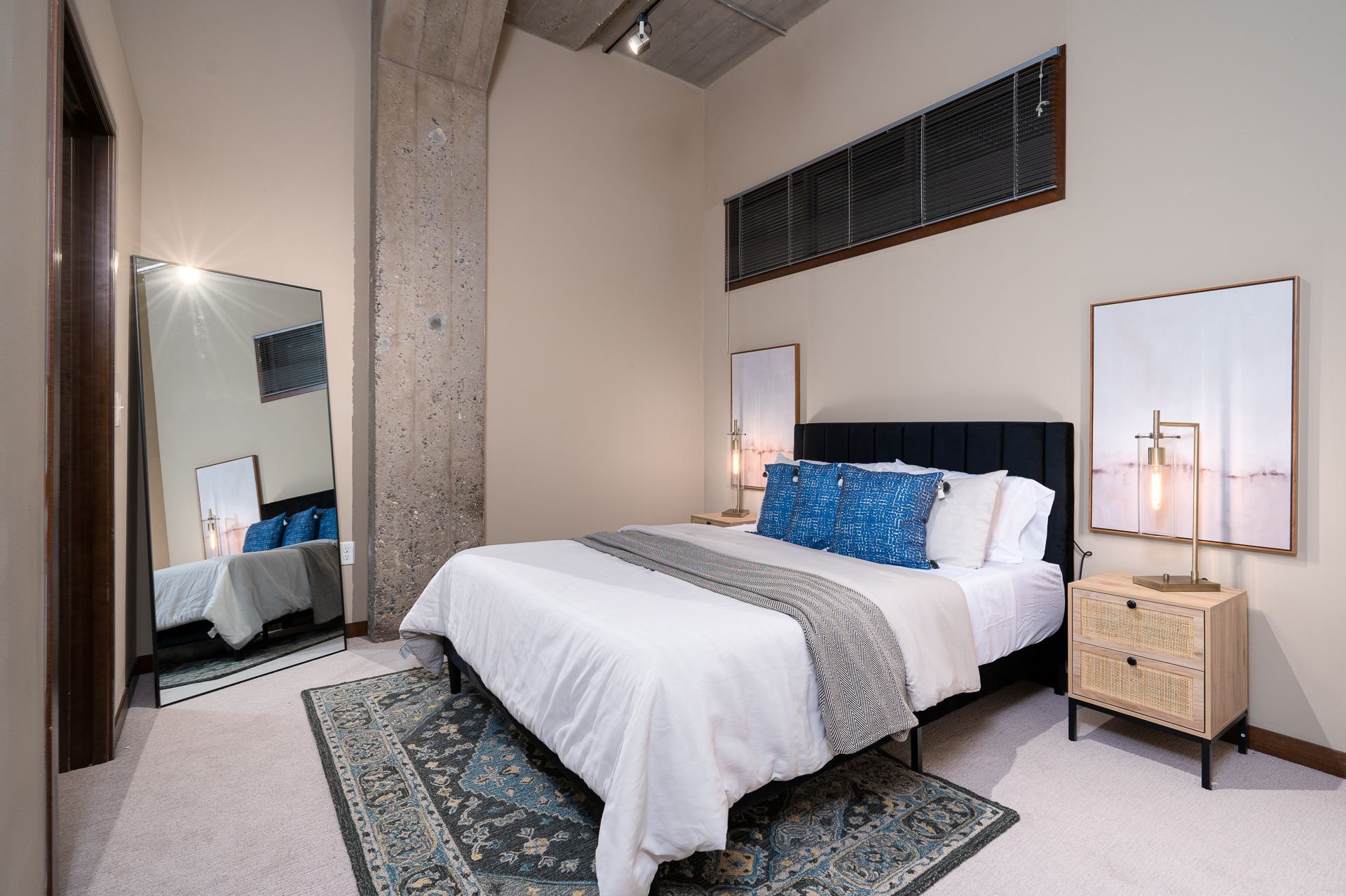 A bedroom with a large bed , nightstand , and mirror.