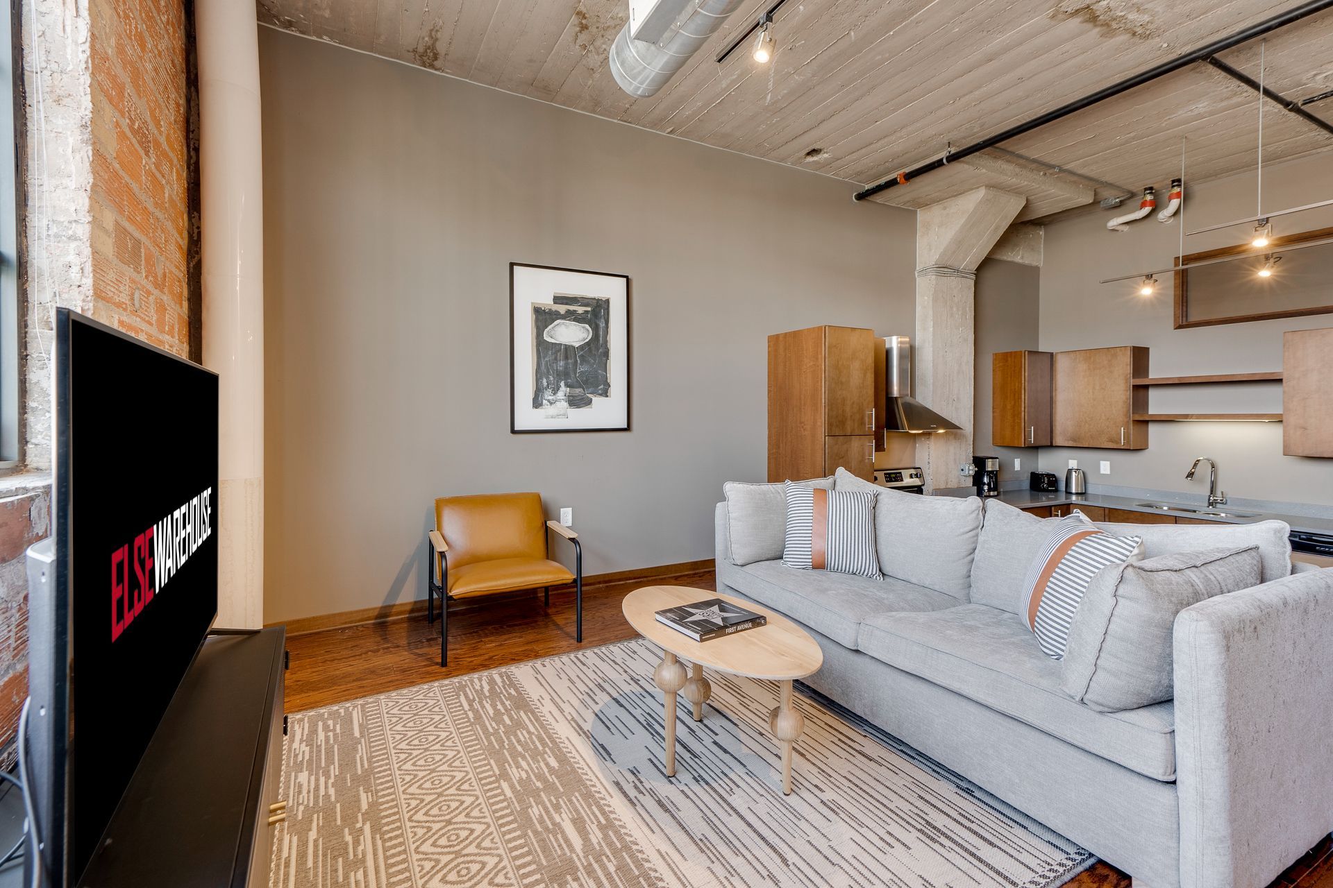 A living room with a couch , chair , coffee table and television.