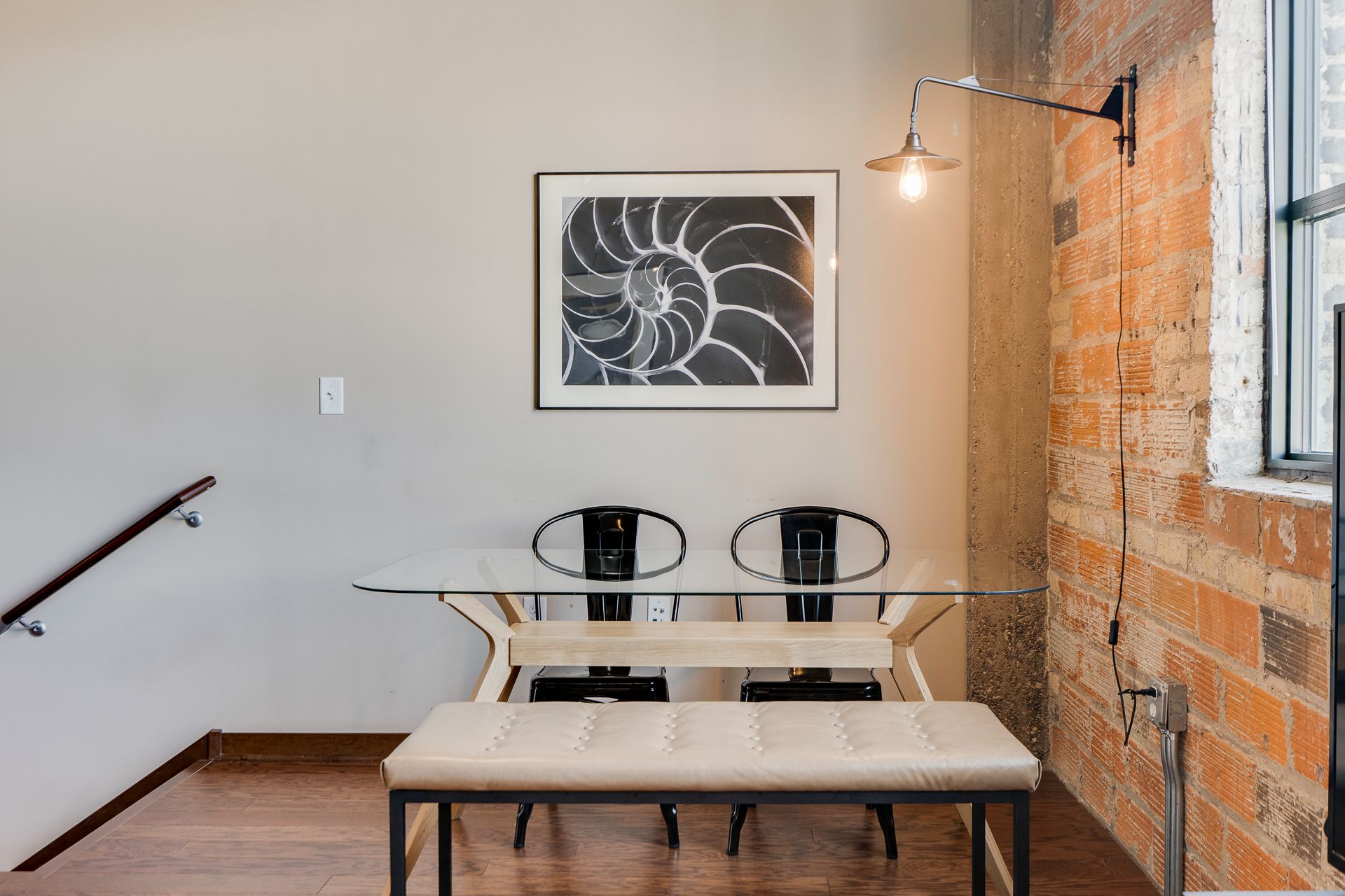 A dining room with a table and chairs and a picture on the wall.