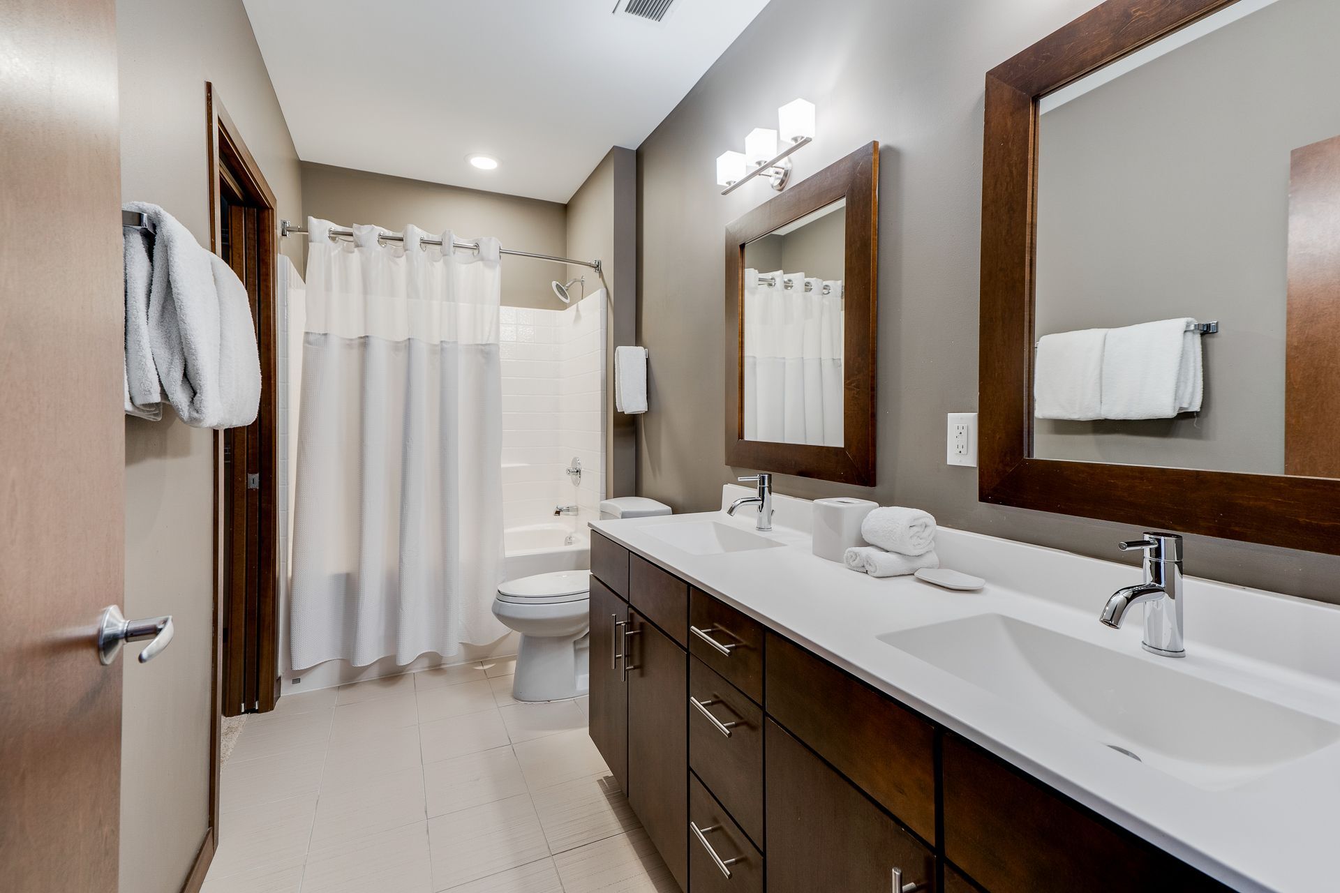A bathroom with two sinks , a toilet , and a shower curtain.
