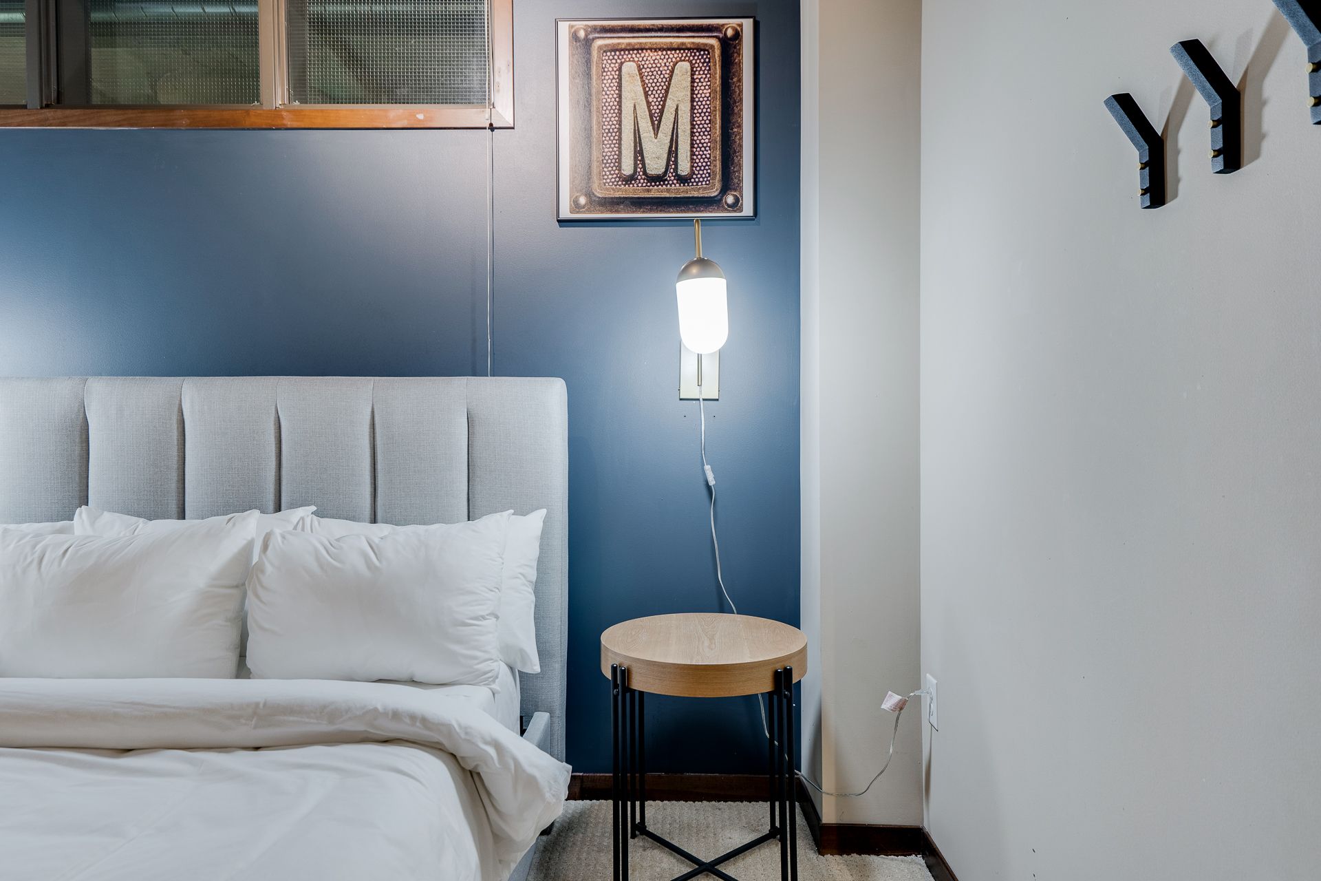 A bedroom with a bed , nightstand and lamp.