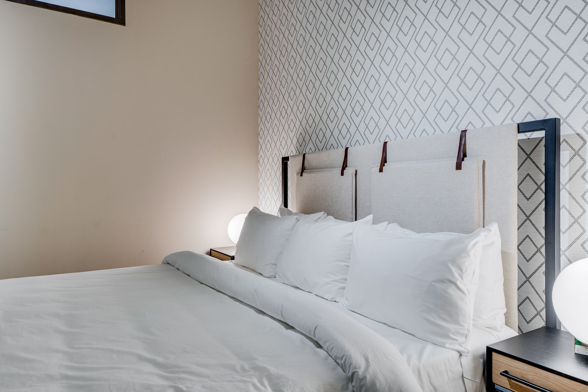 A hotel room with a bed , nightstand , and lamp.