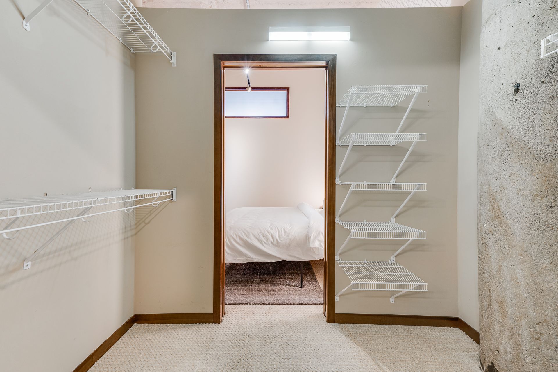 A walk in closet with shelves and a door leading to a bedroom.