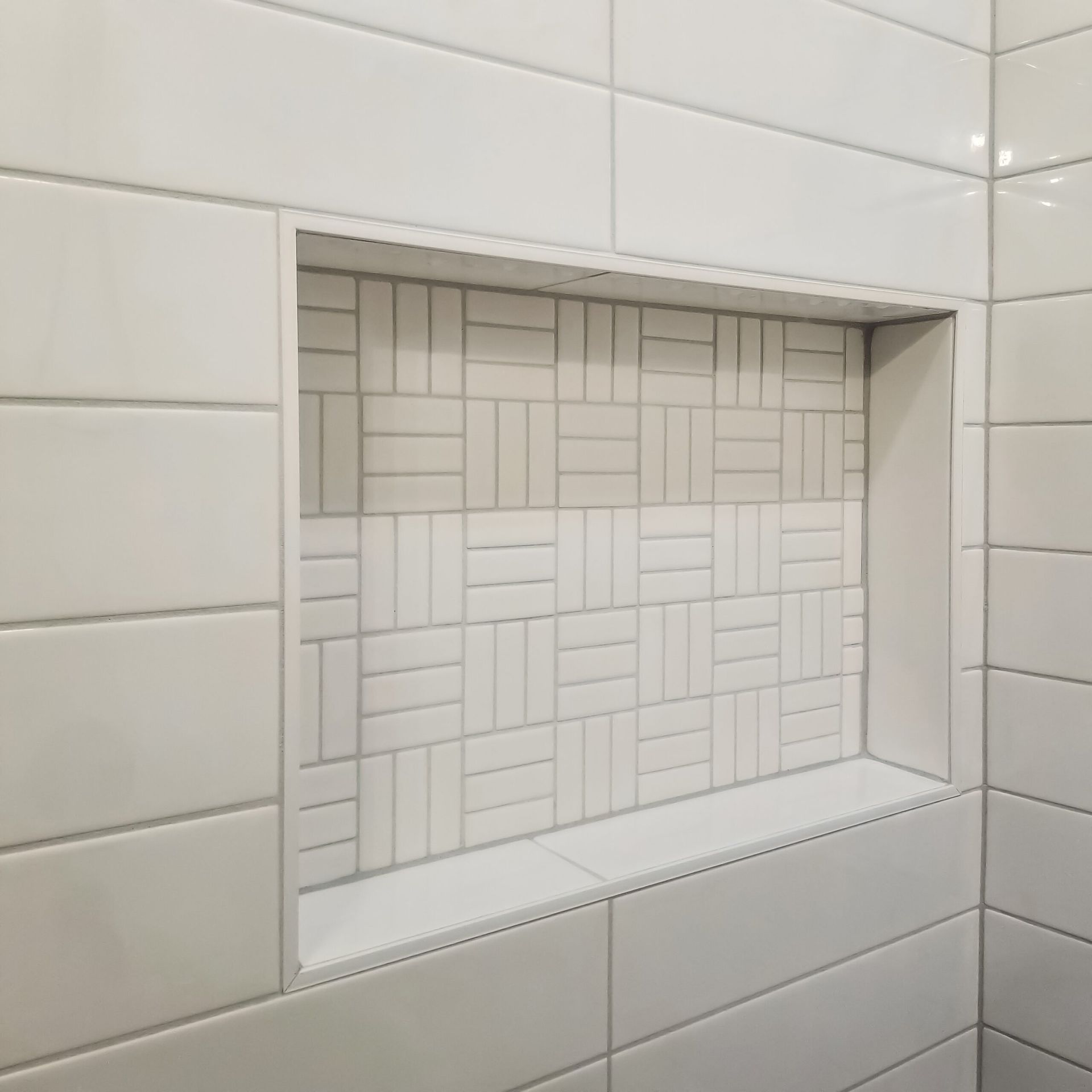 A bathroom with white tiles and a niche in the wall.