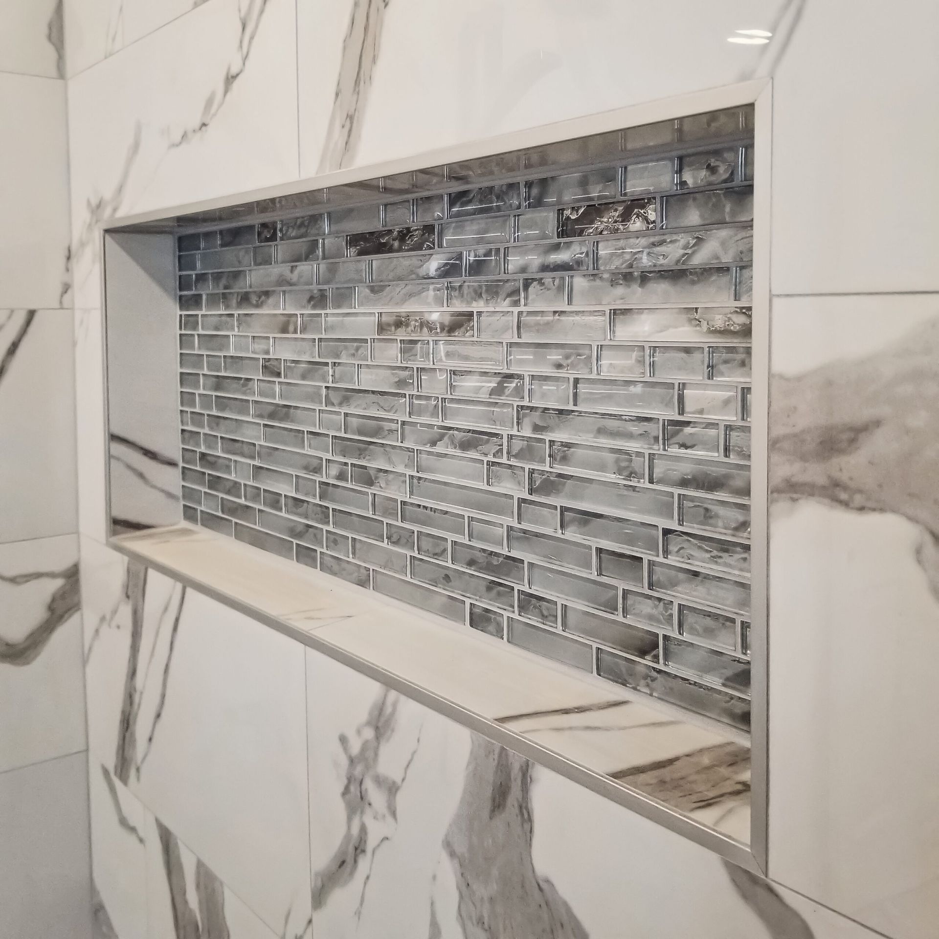 A shower niche in a bathroom with marble tiles
