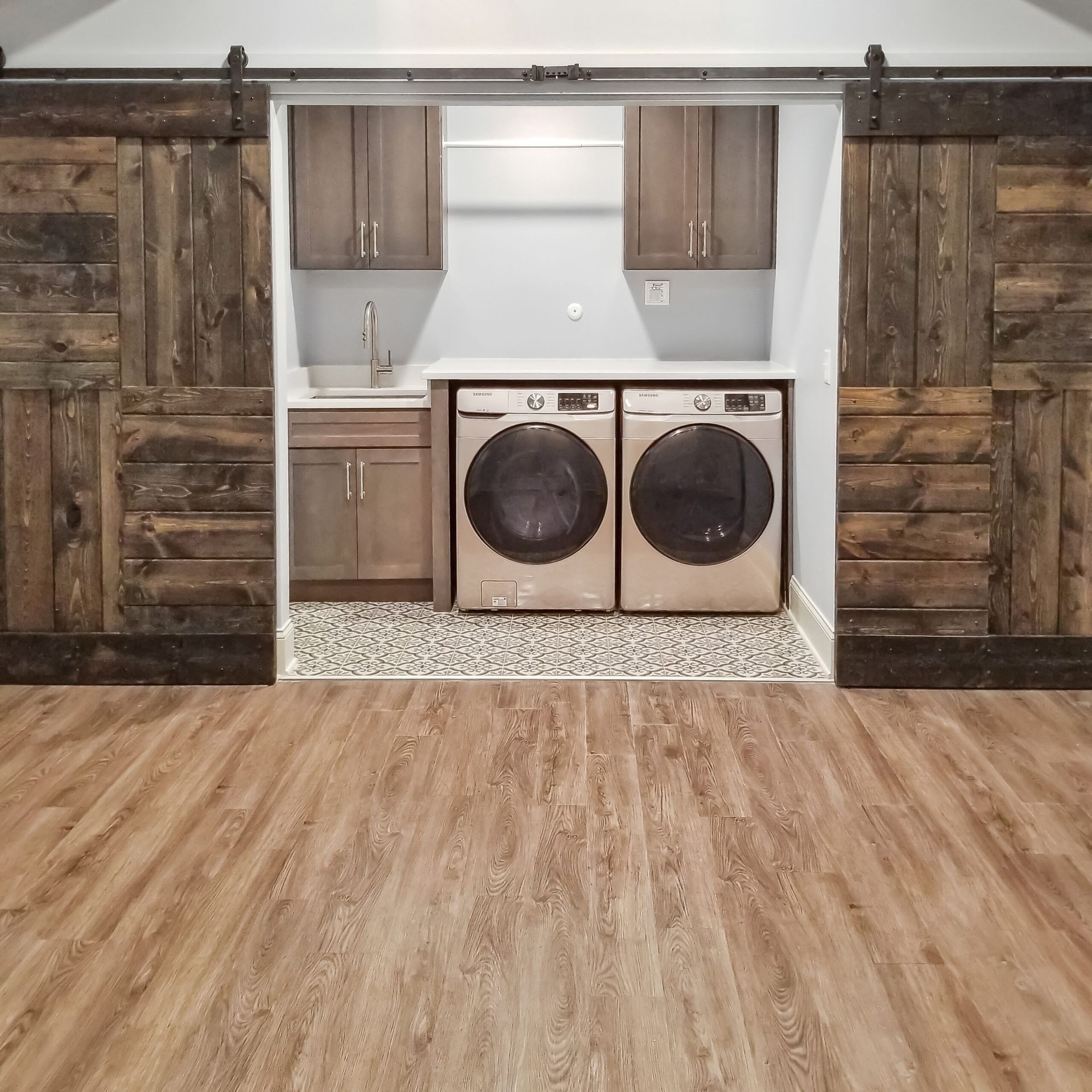 A laundry room with a washer and dryer and sliding barn doors