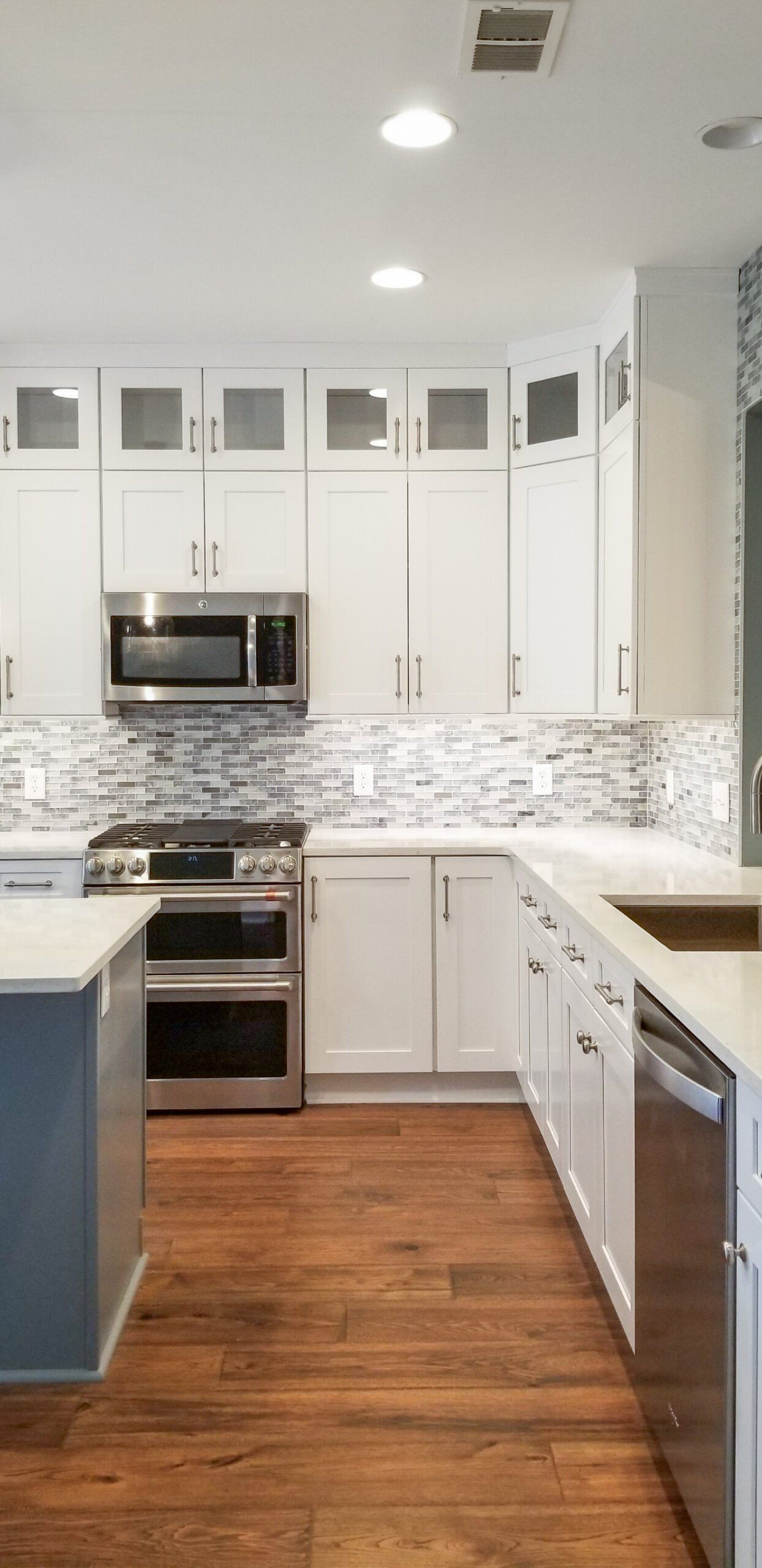 A kitchen with white cabinets , stainless steel appliances , and hardwood floors.