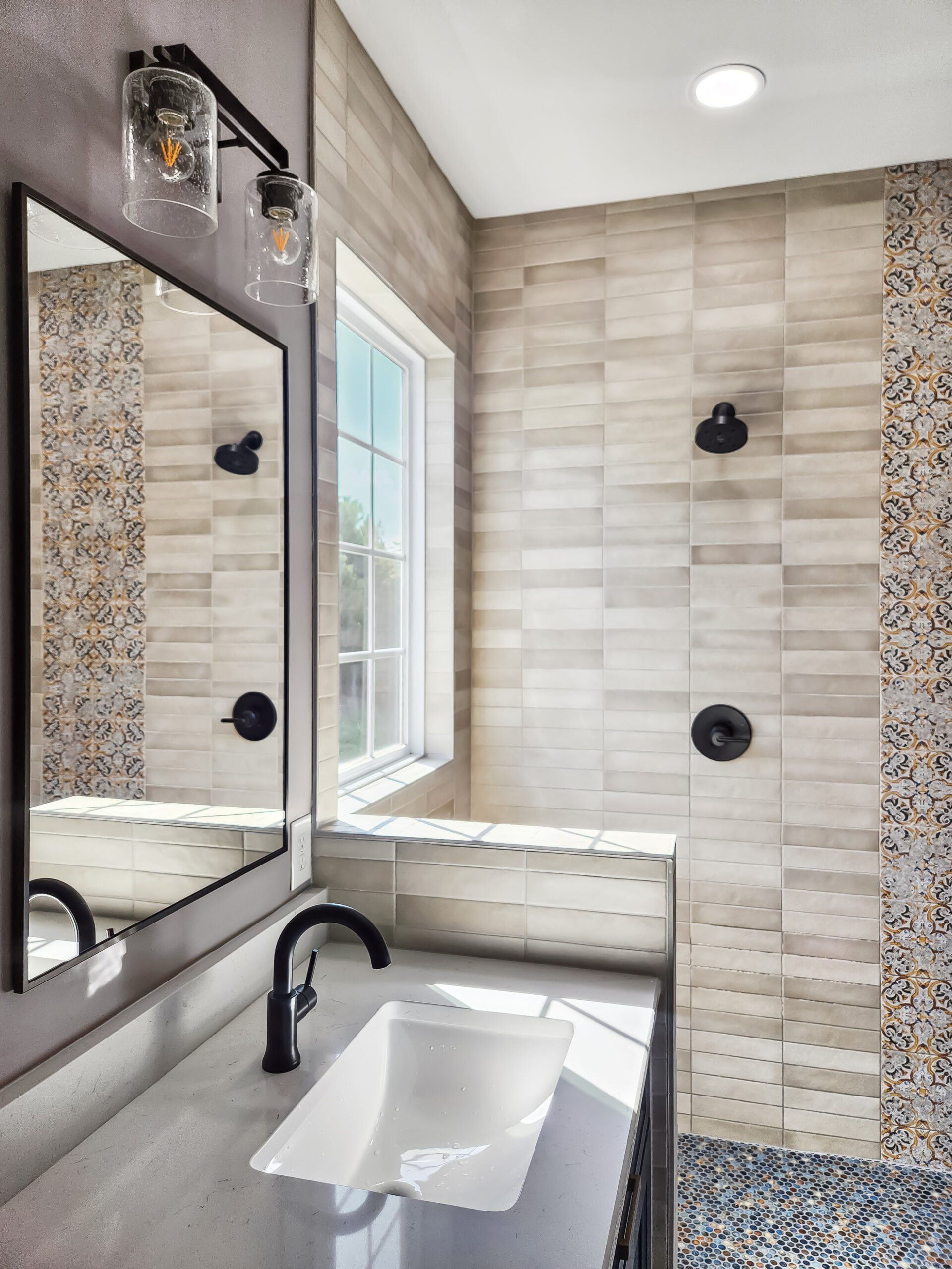 A bathroom with a sink , mirror and shower.
