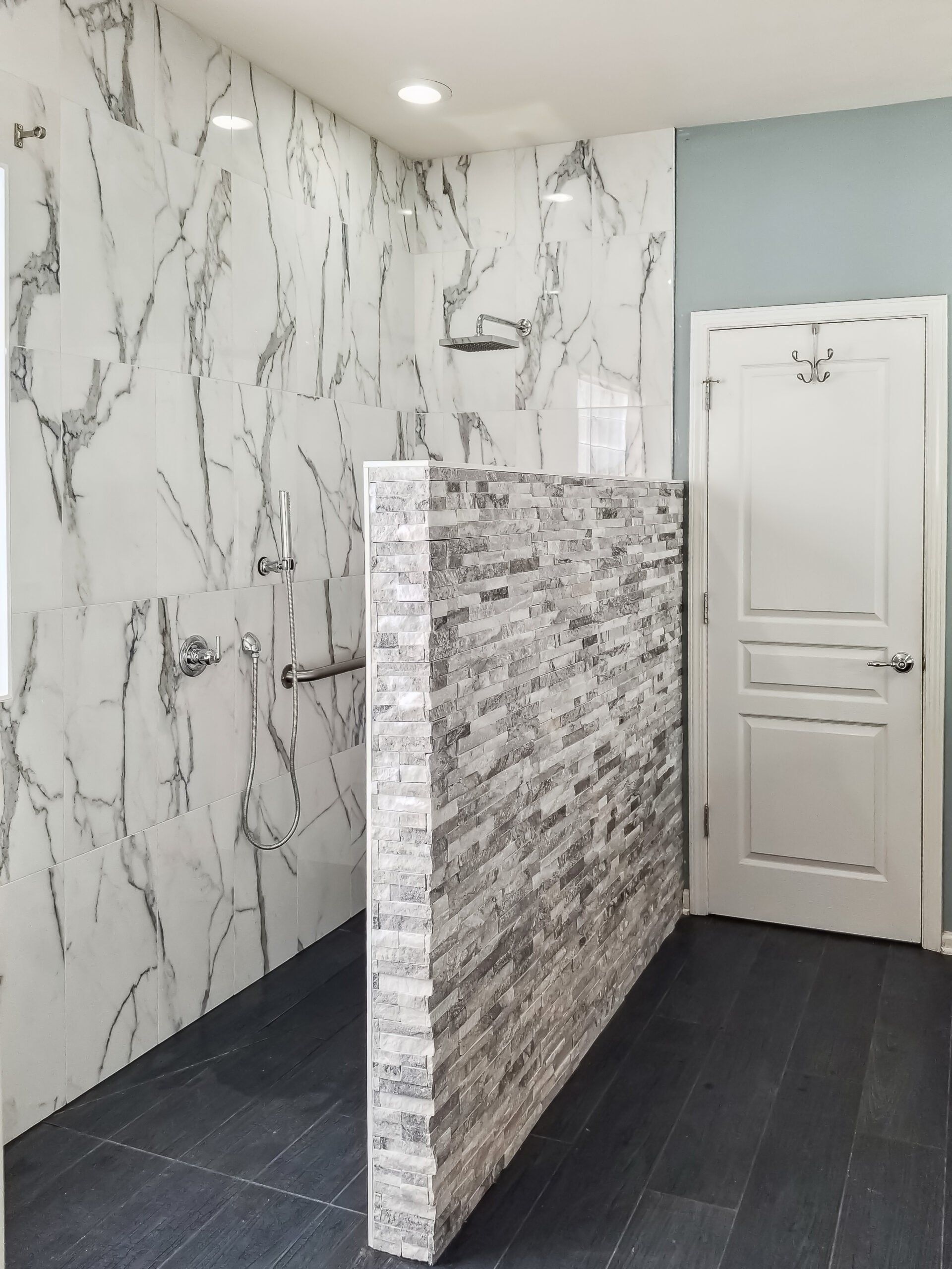 A bathroom with marble walls and a walk in shower.