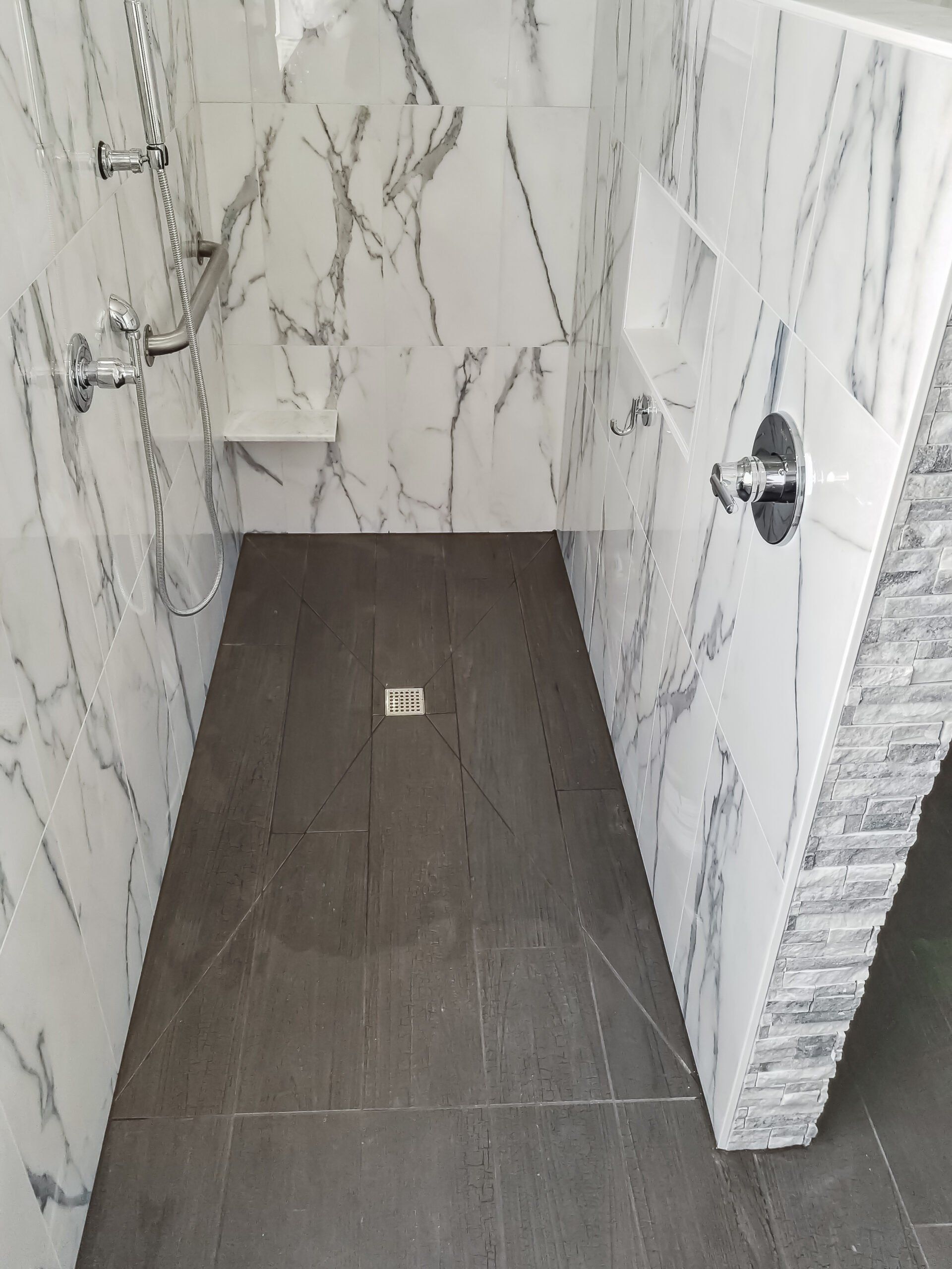 A bathroom with marble walls and a walk in shower.