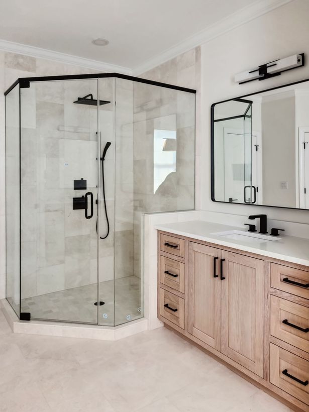 A bathroom with a walk in shower , sink and mirror.